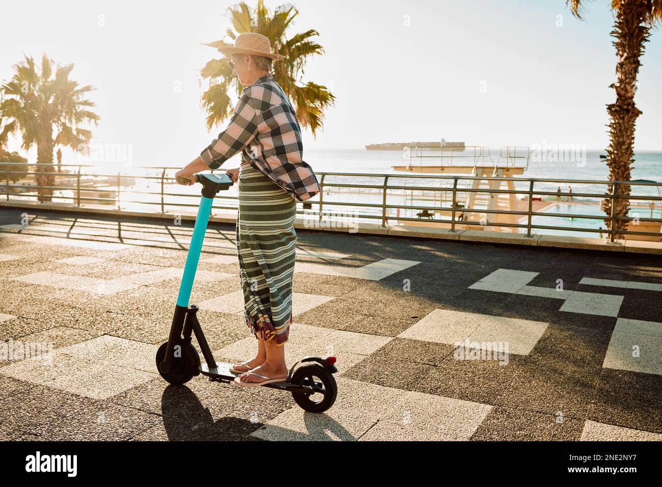 Electric scooter, retirement and woman riding on sidewalk at tropical island beach resort for