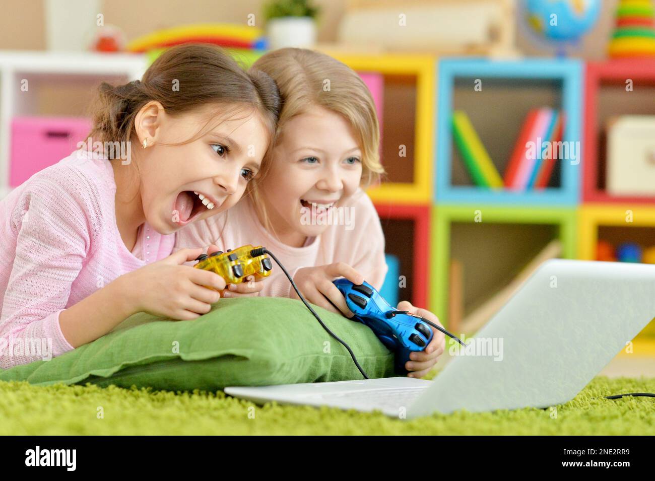 Two teeenage girls playing computer game with laptop Stock Photo - Alamy