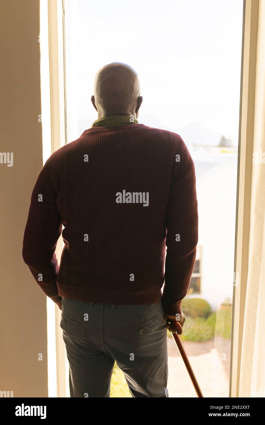 Rear view of african american senior man with walking stick looking out ...