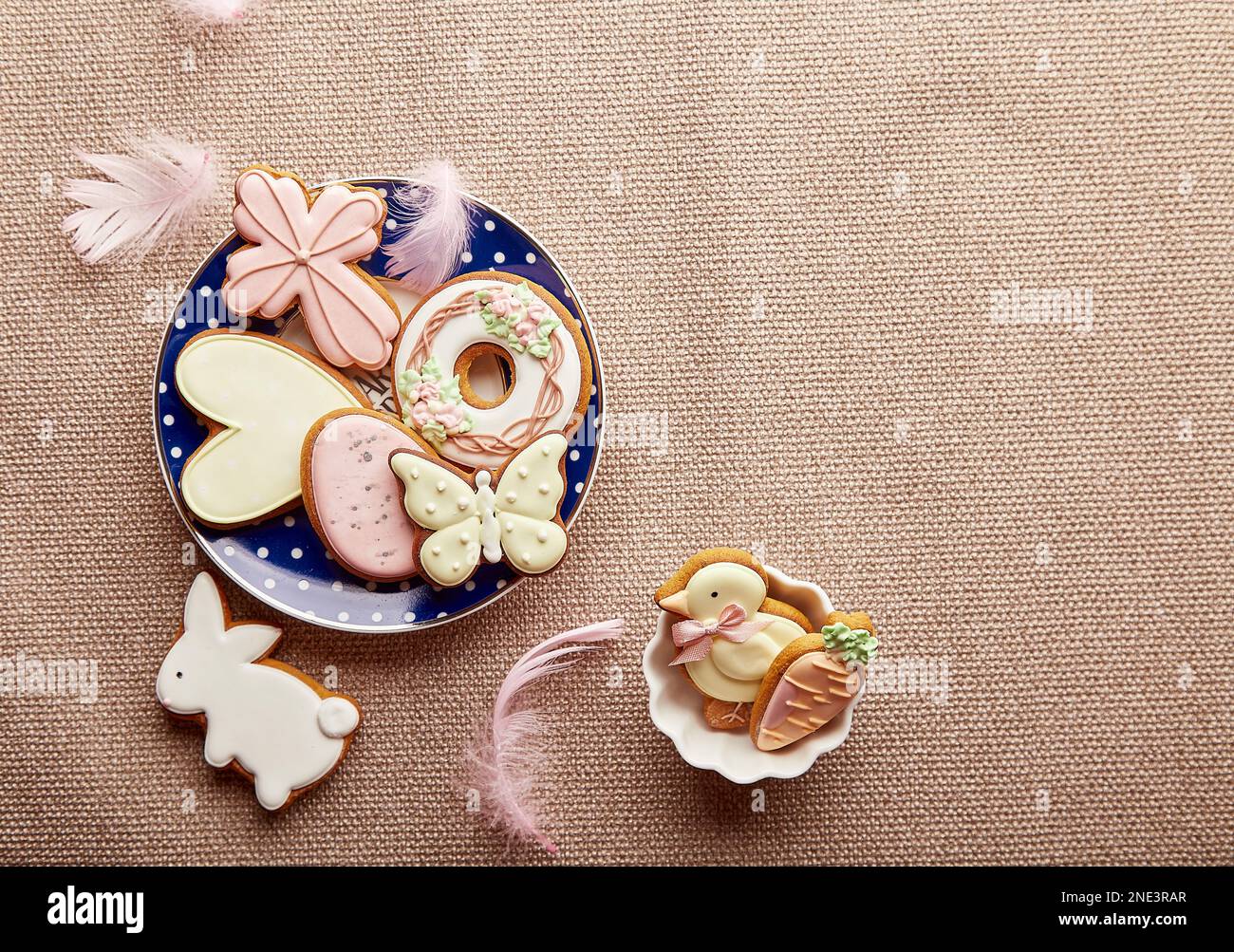 Easter trendy aesthetic background with copy space. Traditional glazing cookies and feathers. Easter food. Stock Photo