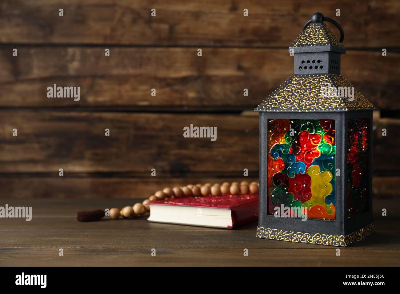 Decorative Arabic lantern, Quran and prayer beads on wooden table