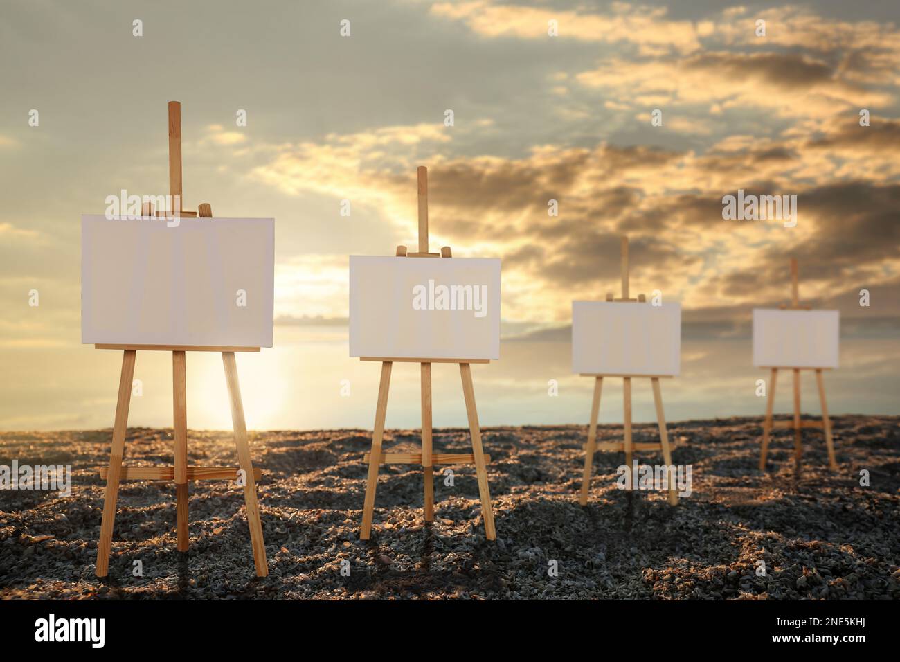 Wooden easels with blank canvases on beach near sea at sunrise Stock