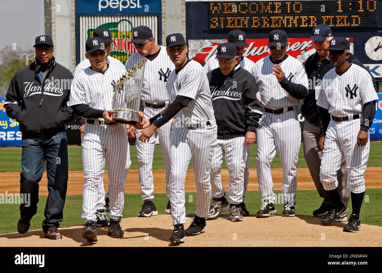 Old time Yankees watch as New York Yankees manager Joe Girardi, second from left, and Yankee captain Derek Jeter carry the World Series trophy from the mound following a pregame ceremony before