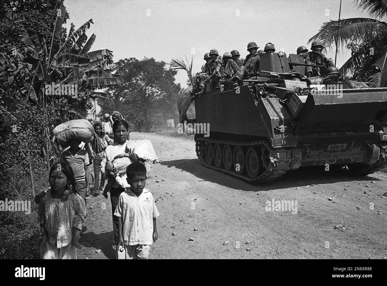 A South Vietnamese armored vehicle with troops aboard rolls by refugees ...