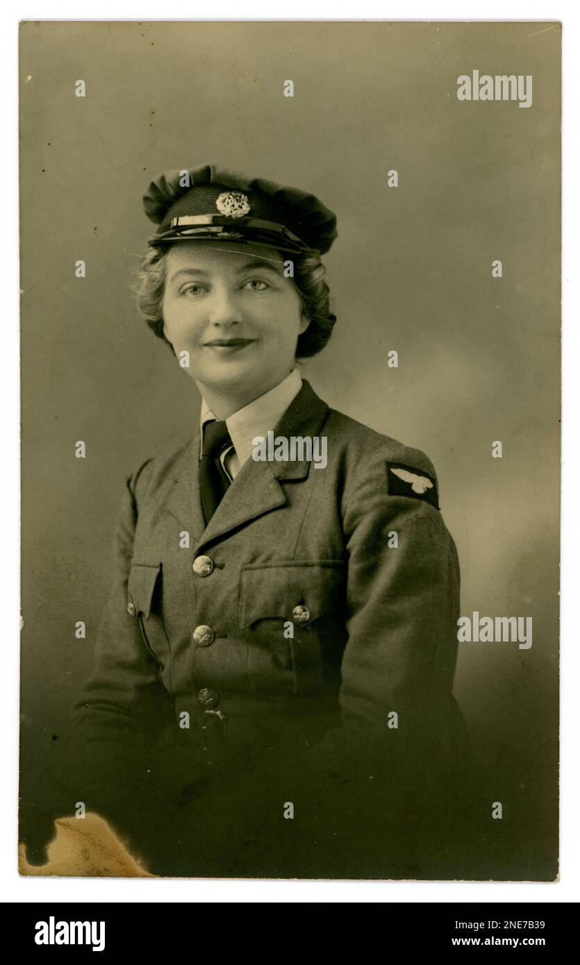 Original WW2 era 1940's postcard of pretty smartly dressed young woman  in Women's Auxiliary Air Force (WAAF) The WAAF was the female auxiliary of the Royal Air Force (RAF) during WW2 and was established in 1939, Possibly a new recruit as lowest of ranks. She wears a cap, jacket in Air Force blue, with wings badge, shirt and tie.  On reverse is written November 30th, circa 1940, U.K. Stock Photo