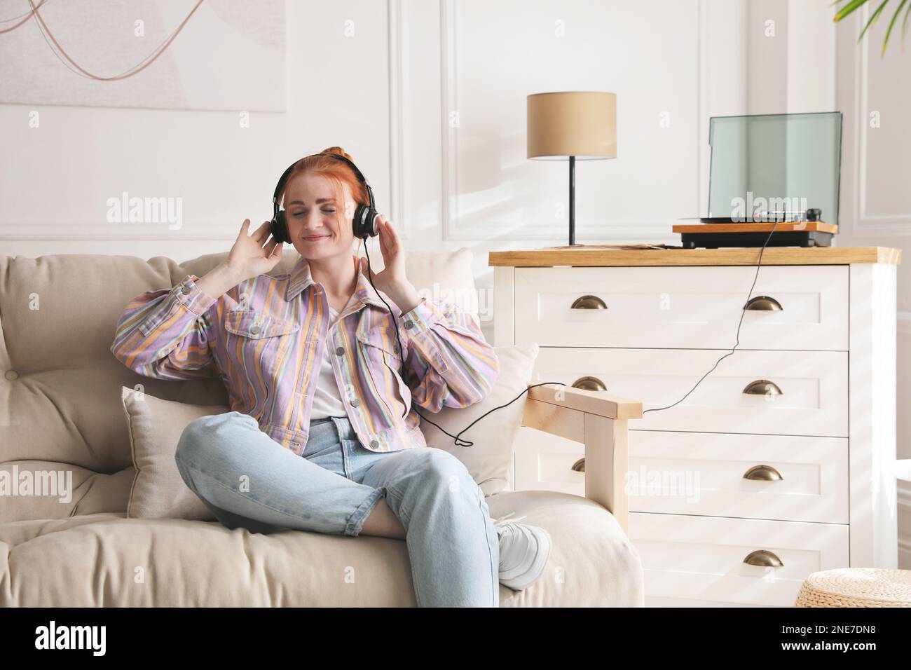 Young woman listening to music with turntable in living room Stock ...