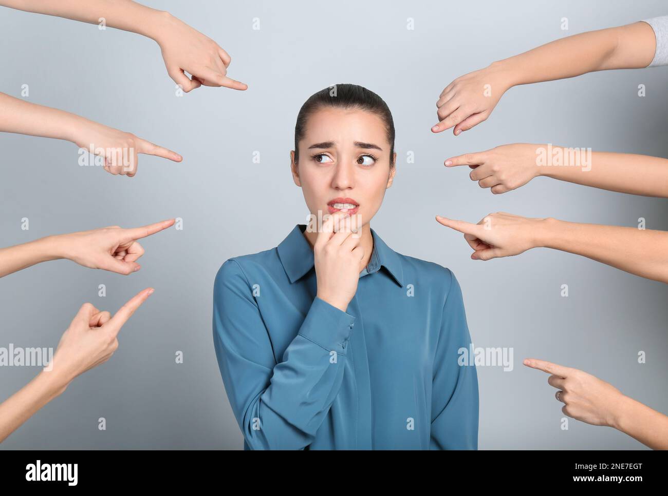 People pointing on emotional businesswoman against light grey background. Corporate social responsibility concept Stock Photo