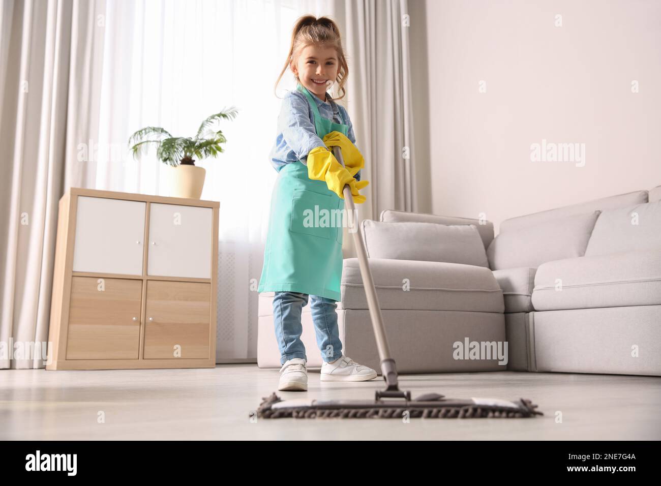 Little girl mopping floor in living room at home Stock Photo Alamy