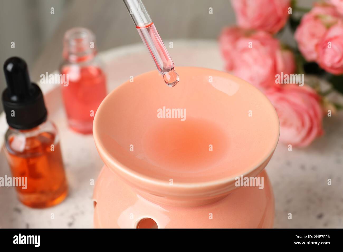 Dripping essential oil into aroma lamp on white tray, closeup Stock