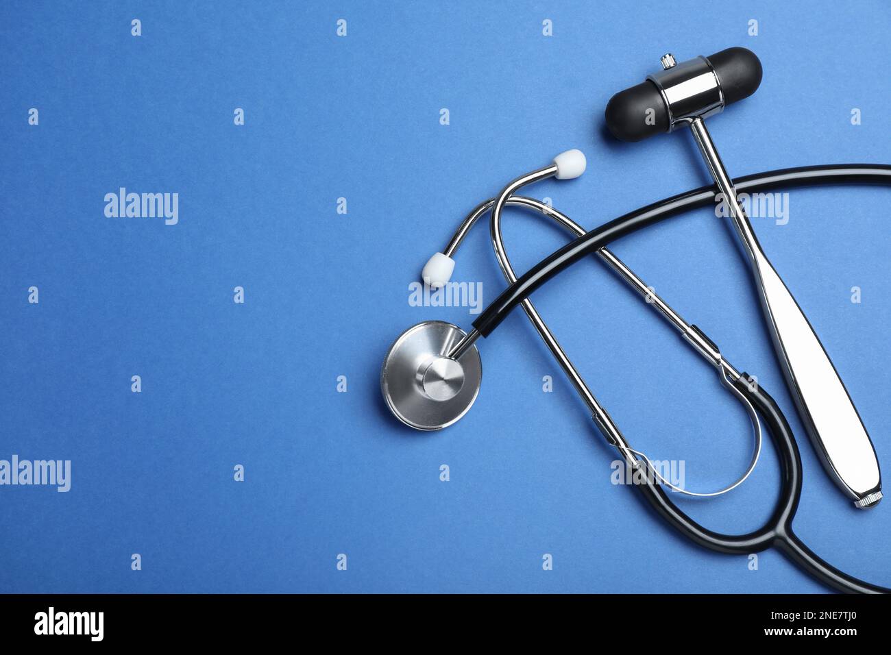 Reflex hammer, stethoscope and space for text on blue background, flat