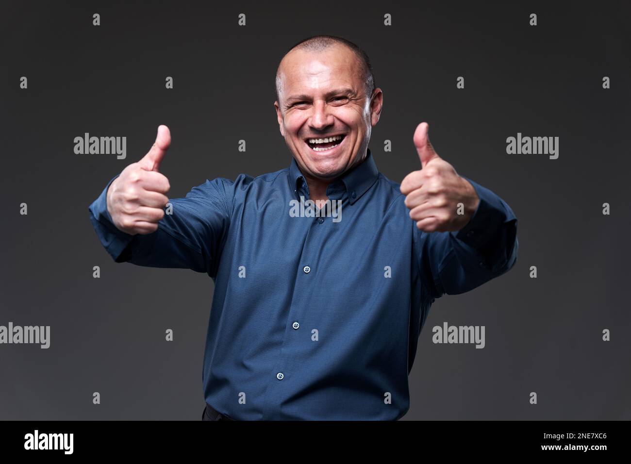 Happy businessman showing thumbs up sign, at the end of a done deal, isolated on gray background Stock Photo