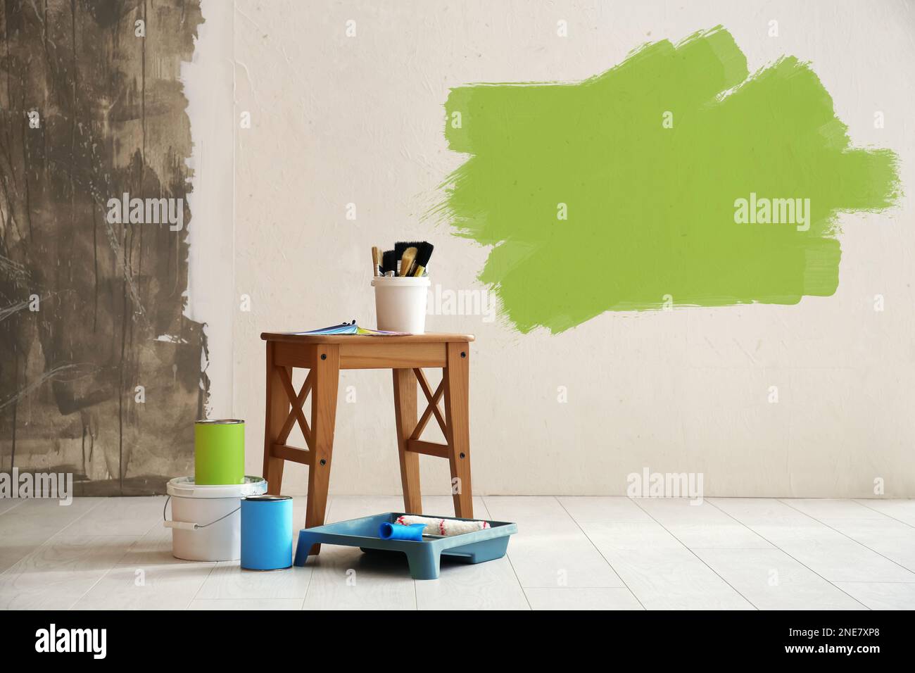 Set with decorator's tools and paint on floor near white wall Stock