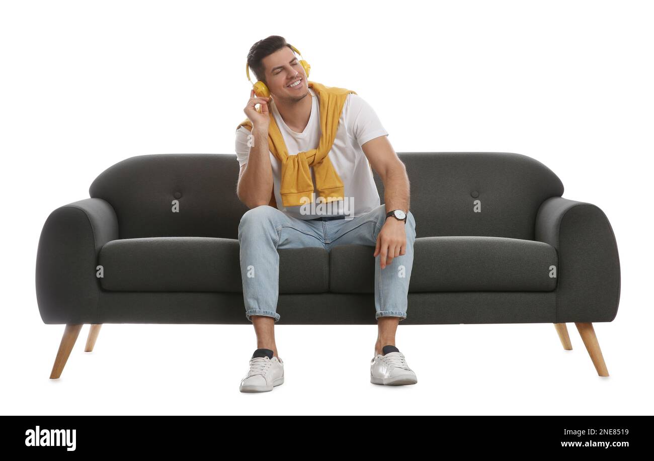 Man listening to music on comfortable grey sofa against white ...