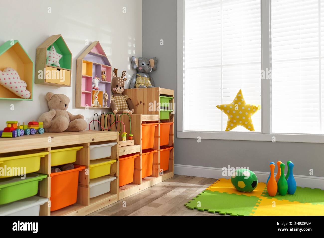 Stylish playroom interior with shelving unit and different soft toys Stock Photo