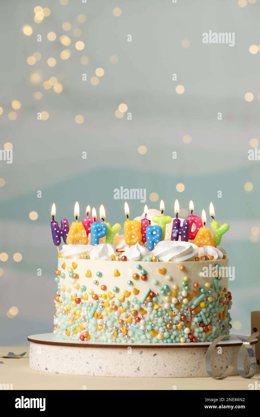 Beautiful birthday cake with burning candles and decor on white table ...