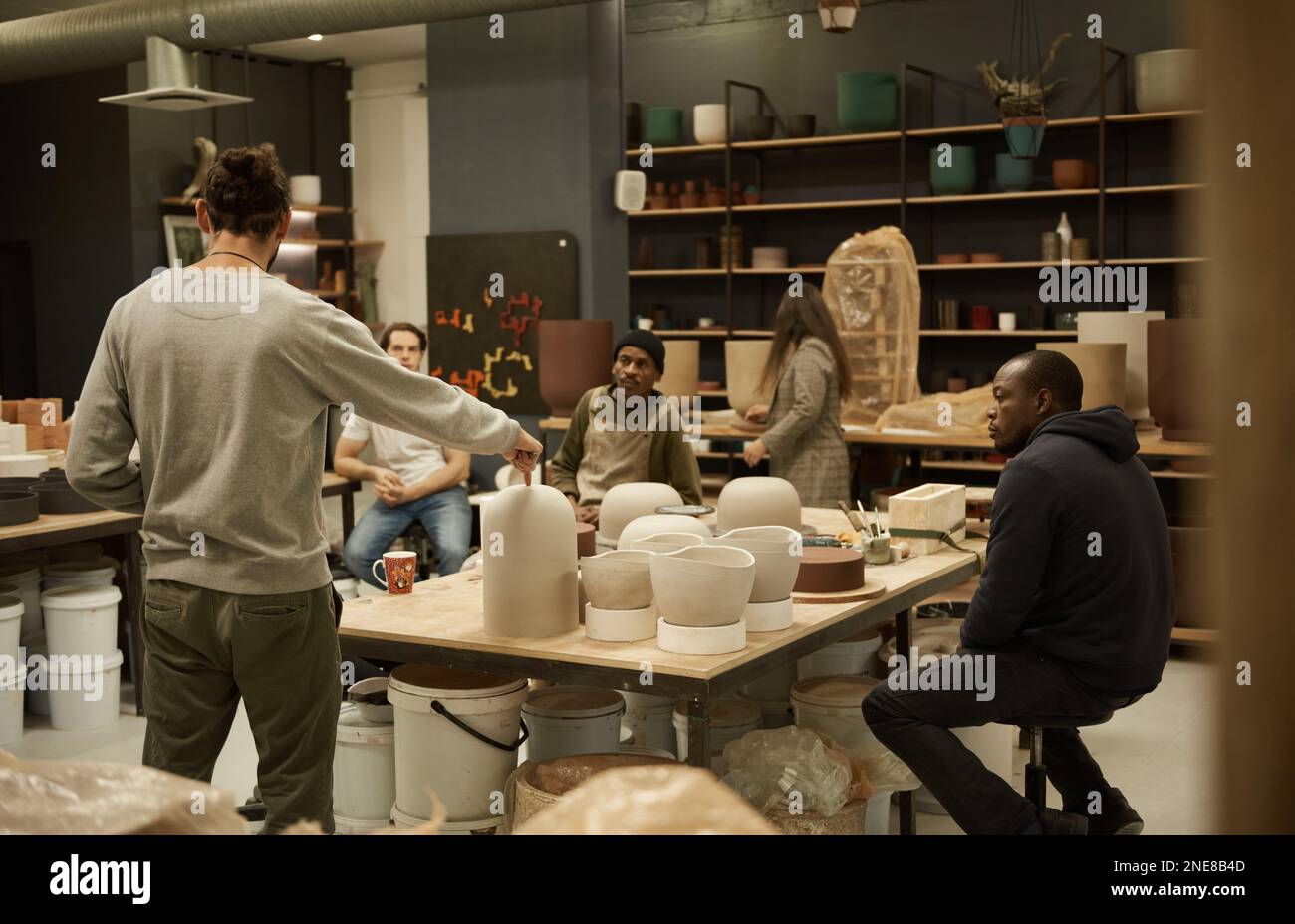 Manager discussing designs with workers in a ceramics studio Stock Photo