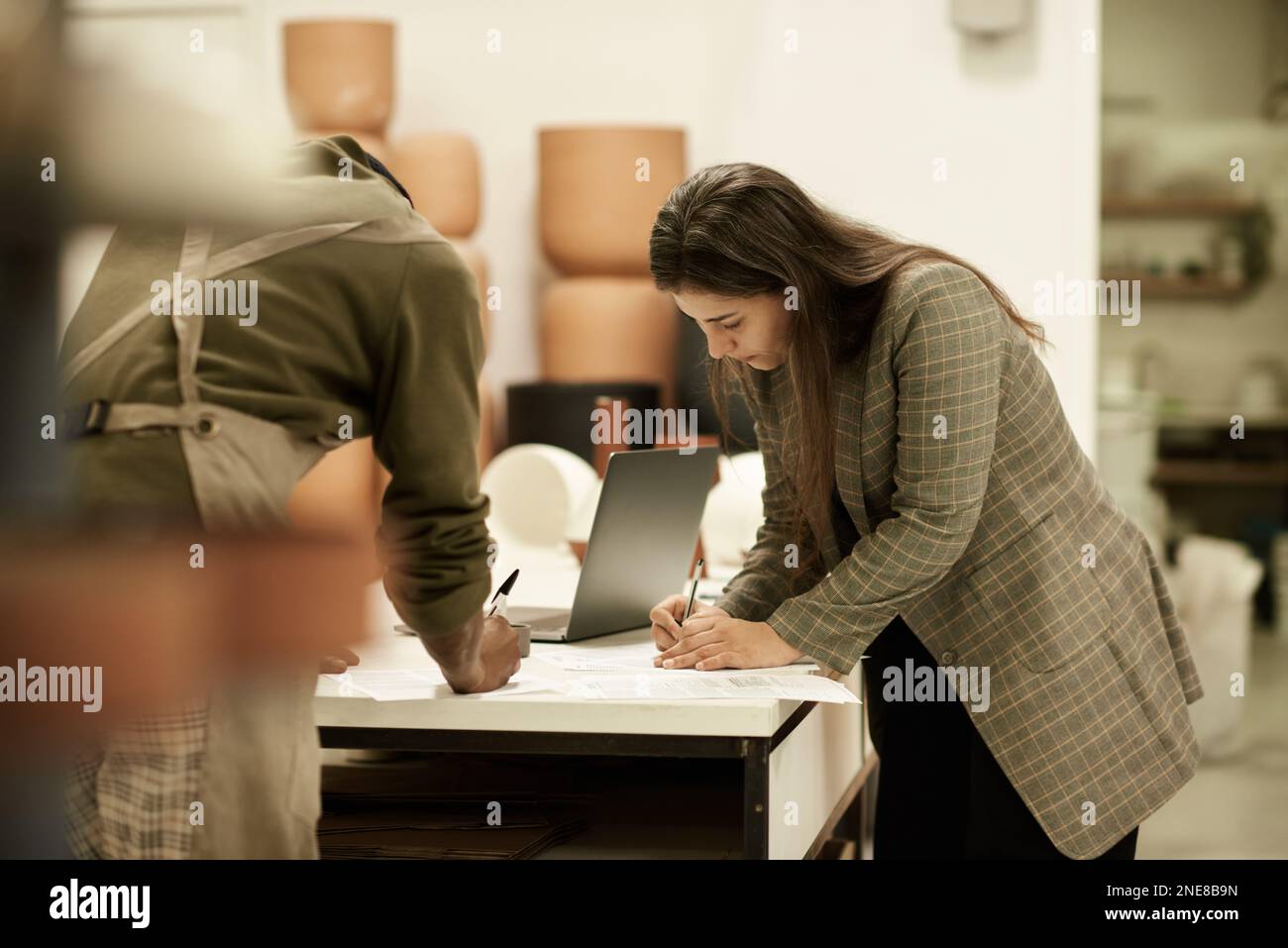 Ceramics studio manager and a colleague working at a table Stock Photo