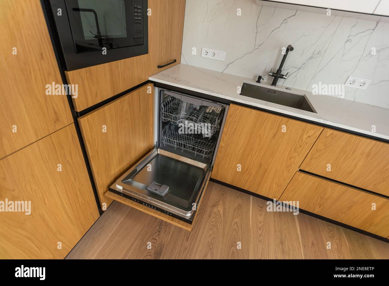 Modern kitchen with empty Builtin dishwasher with opened door