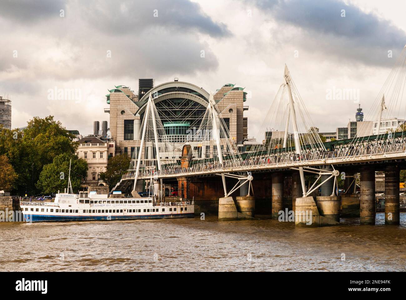 View from the South bank of the Thames river of Charing Cross station, the Hungerford rail bridge and the adjacent Golden Jubilee footbridge. Stock Photo