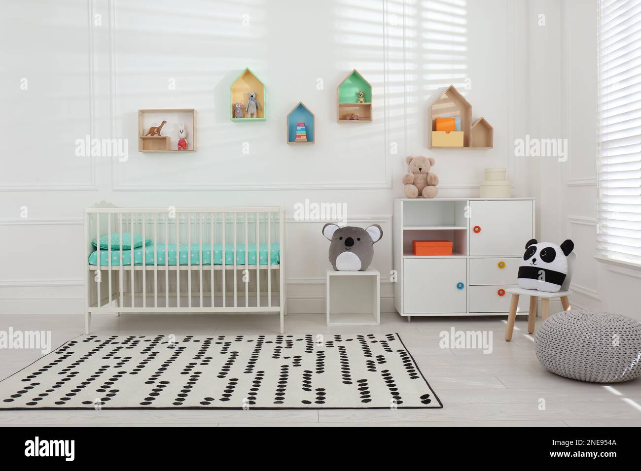 Comfortable crib near wall with color shelves in baby room. Interior