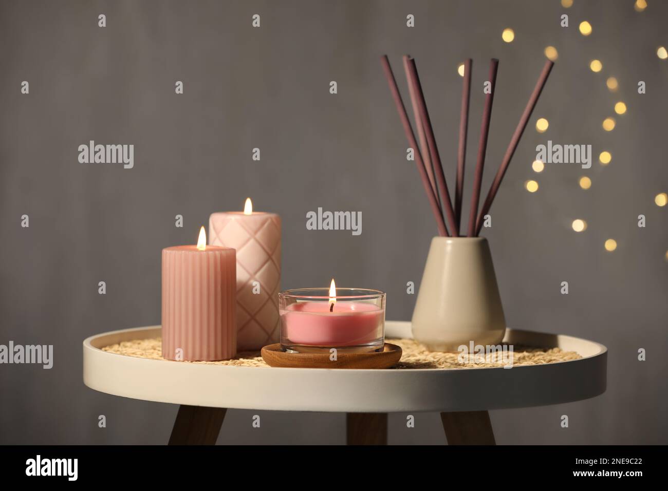 Burning candles and reed diffuser on table against grey background Stock Photo