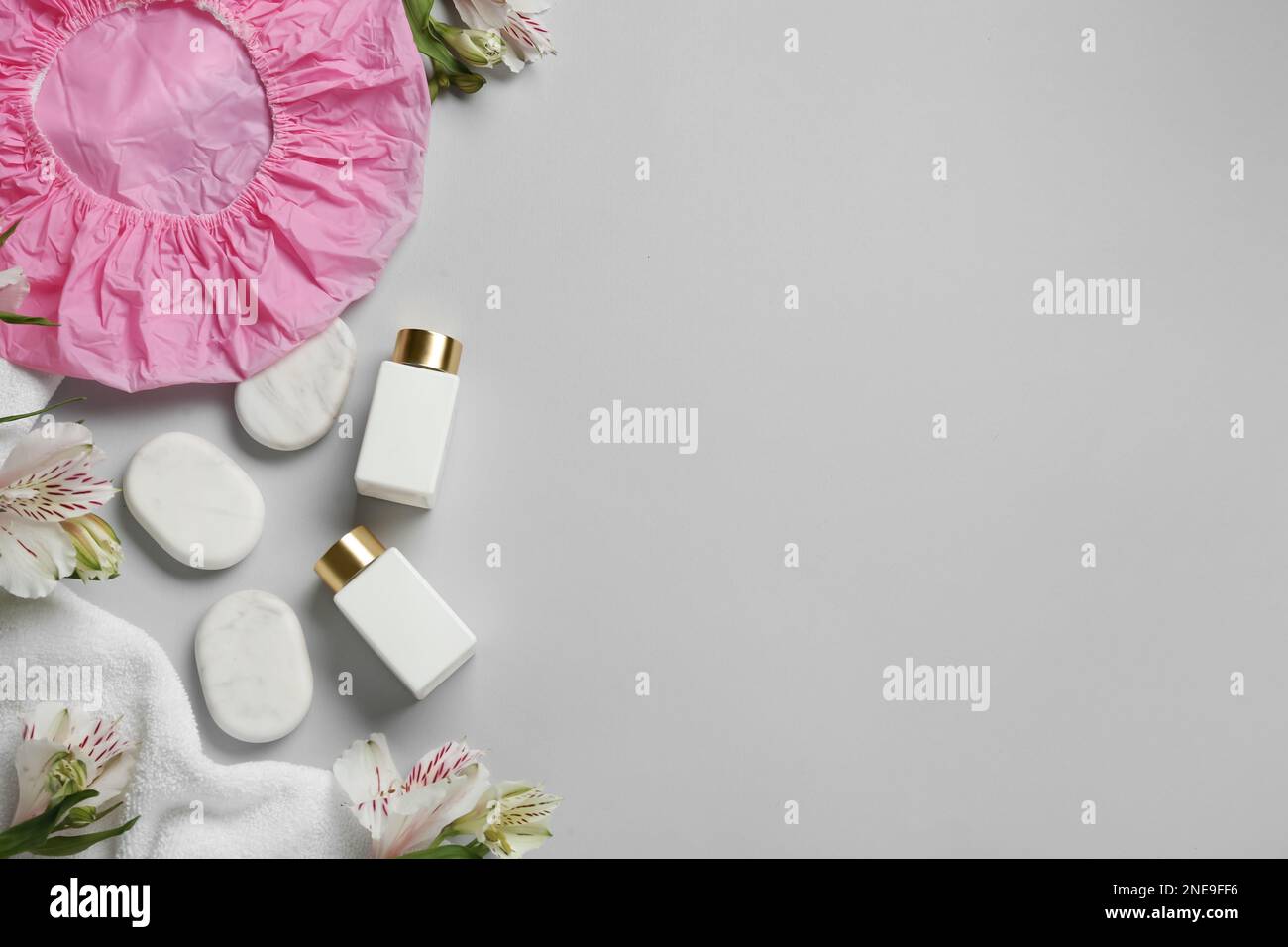 Flat lay composition with shower cap and spa stones on grey background ...