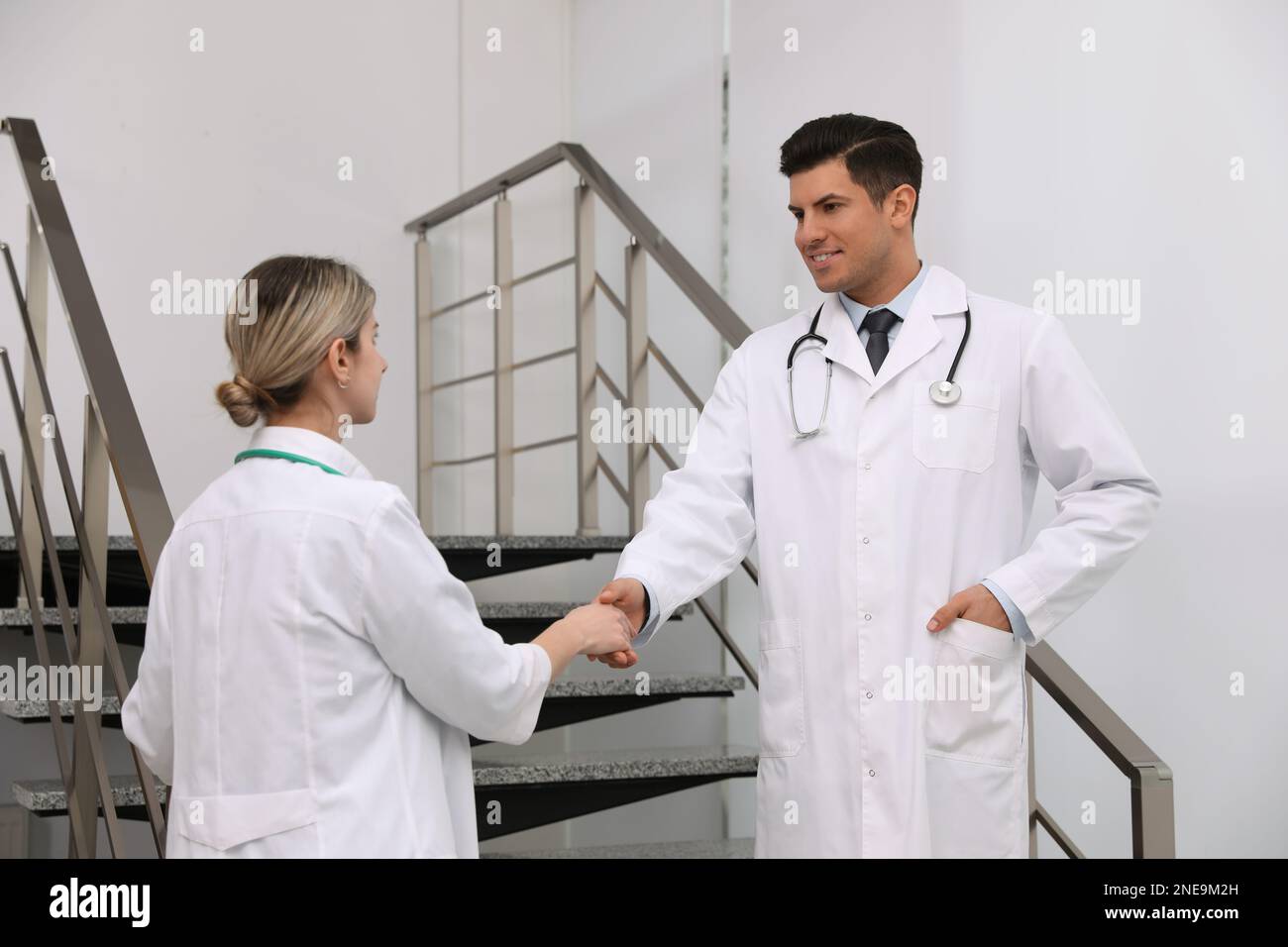 Doctors greeting with handshake on stairs in clinic Stock Photo