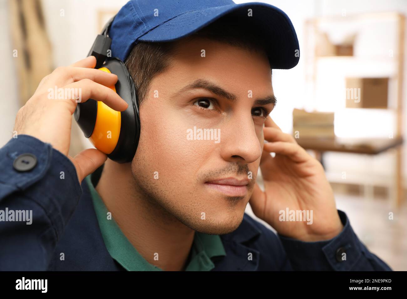 Worker wearing safety headphones indoors. Hearing protection device