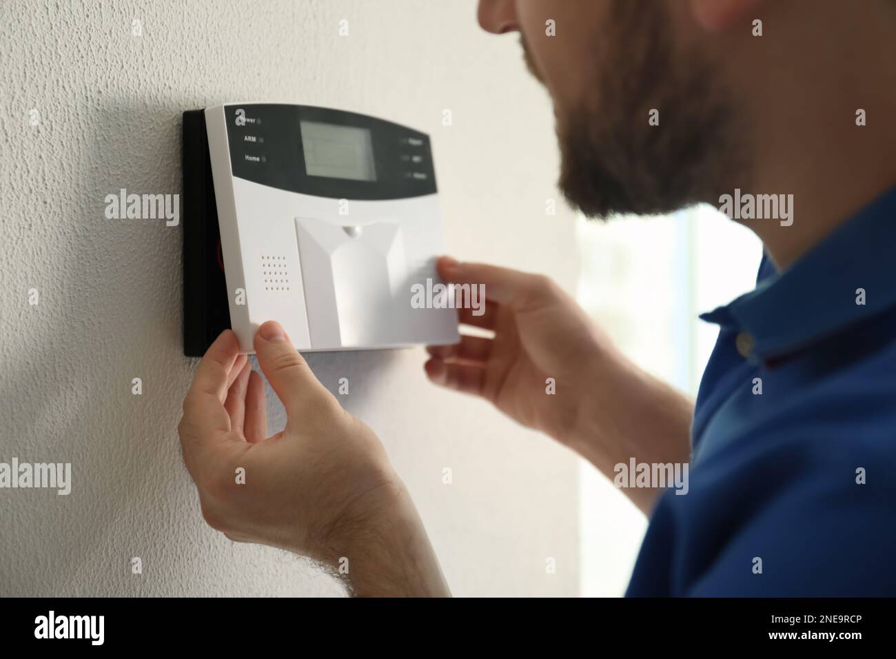 Man installing home security system on white wall in room, closeup Stock Photo
