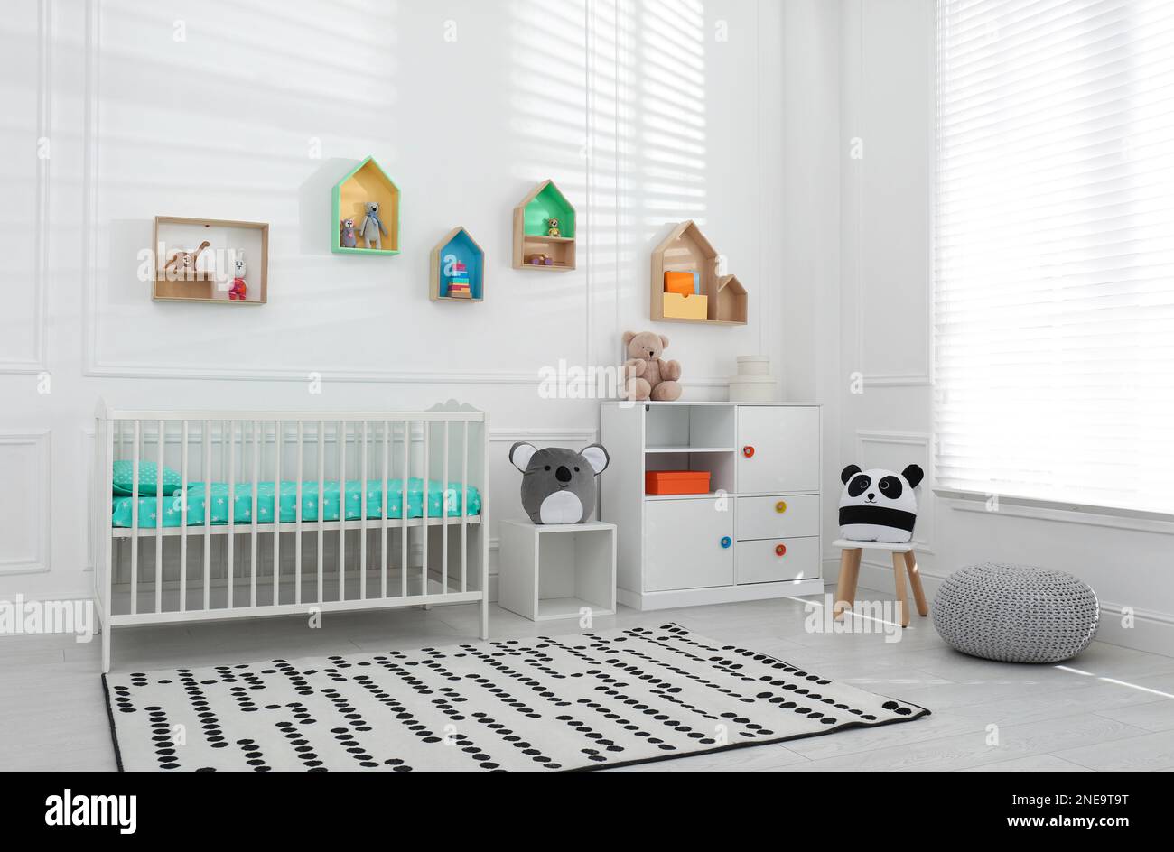 Comfortable crib near wall with color shelves in baby room. Interior