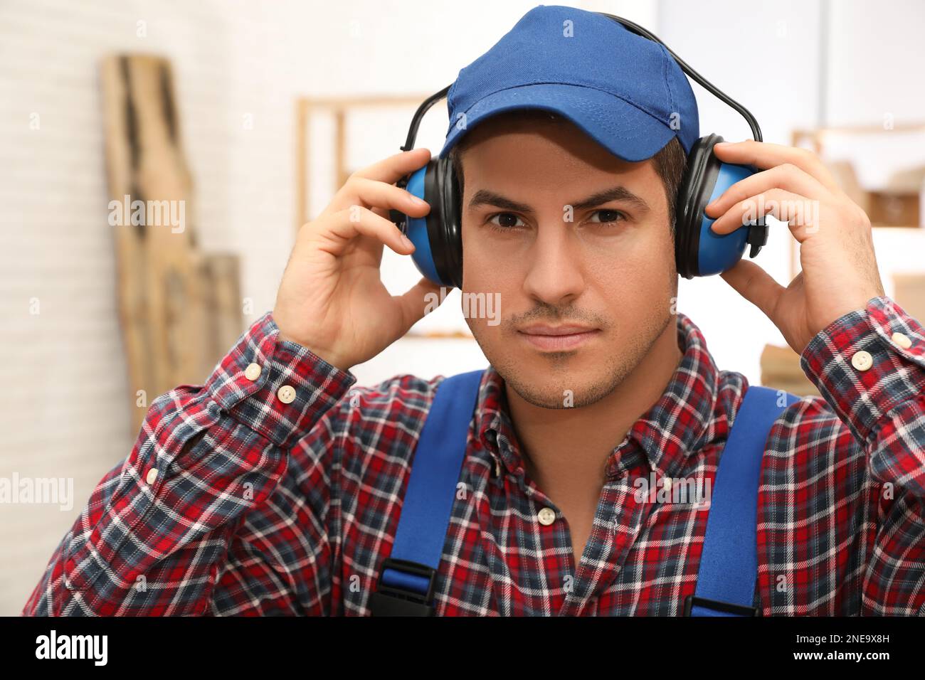 Worker wearing safety headphones indoors. Hearing protection device