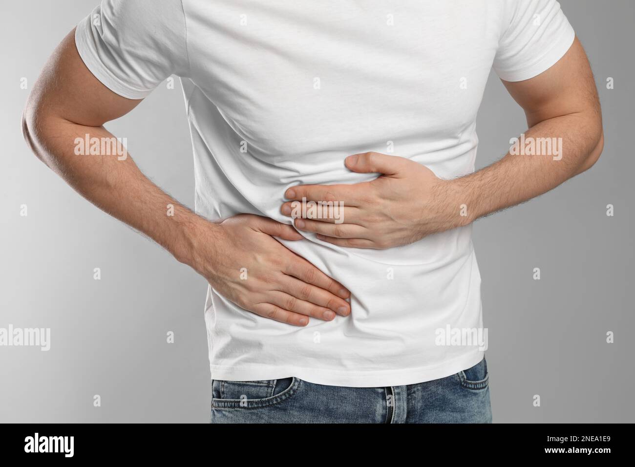 Man suffering from pain in lower right abdomen on light grey background