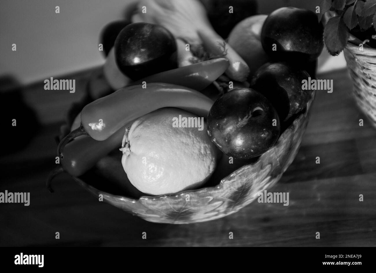 Fruit bowl containing fennel , plums , red chillies and lemons in monochrome Stock Photo