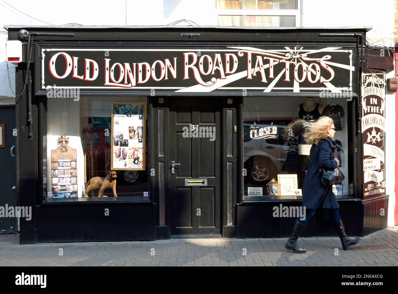 exterior of old london road tattoos, a tattoo shop in kingston upon thames, surrey, england, seen with a woman walking past Stock Photo