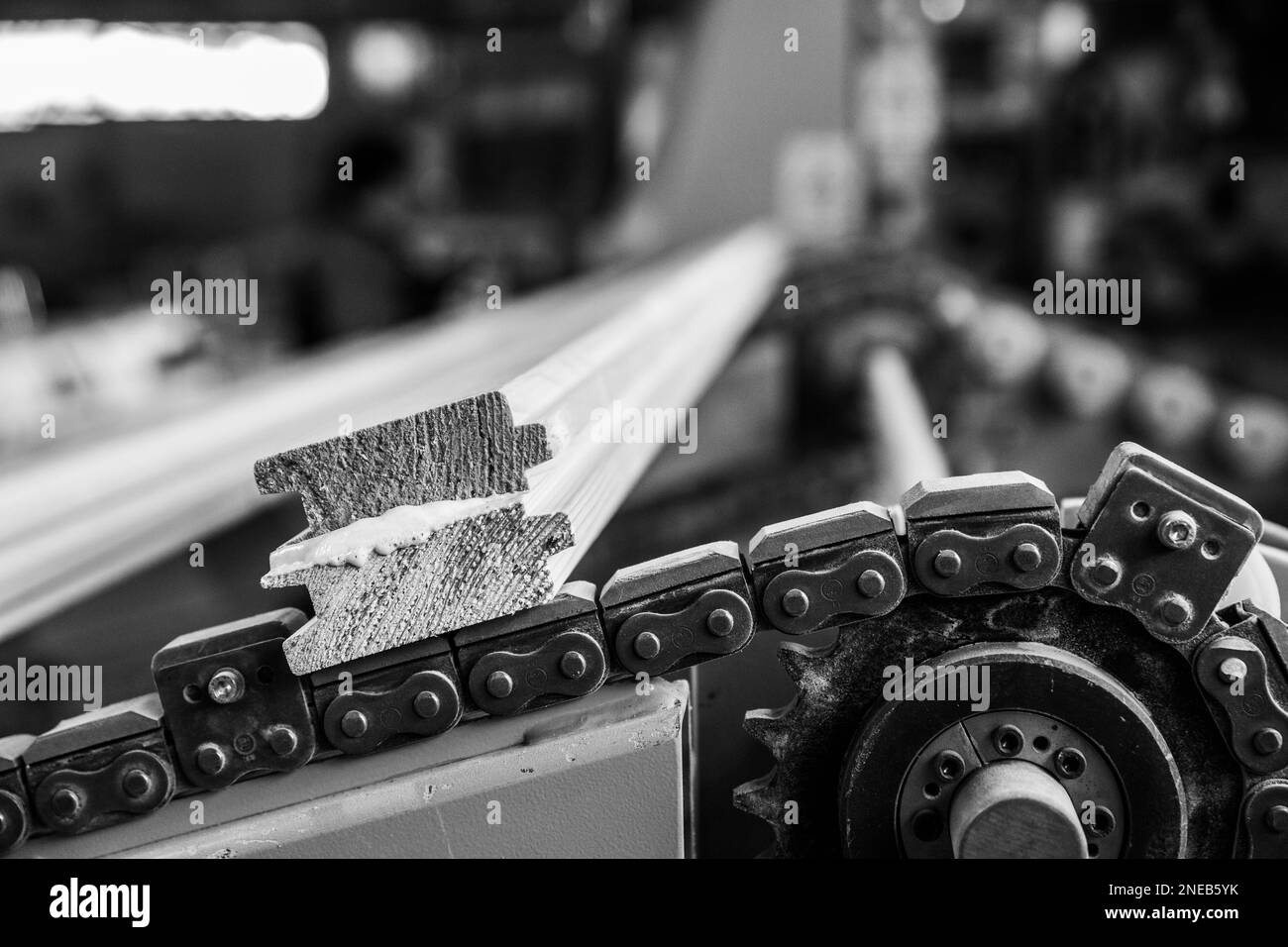 A grayscale closeup shot of a motor chain with timbers on it. Stock Photo