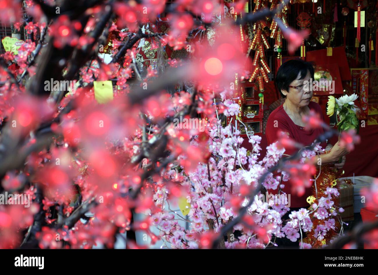 An ethnic Chinese woman selects artificial flowers for the Chinese New Year at a shop