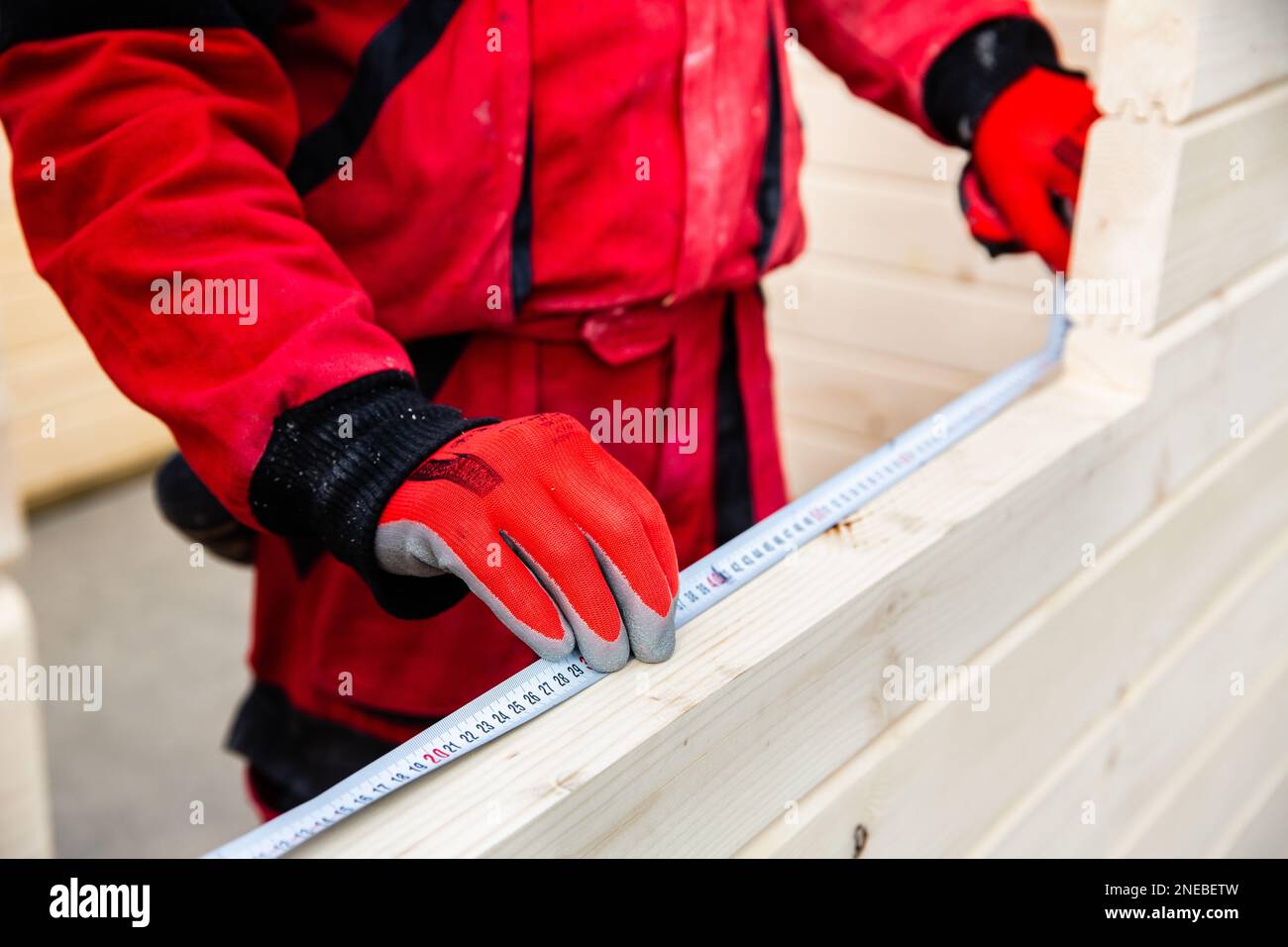 A construction worker measures the timber of a new wooden building ...