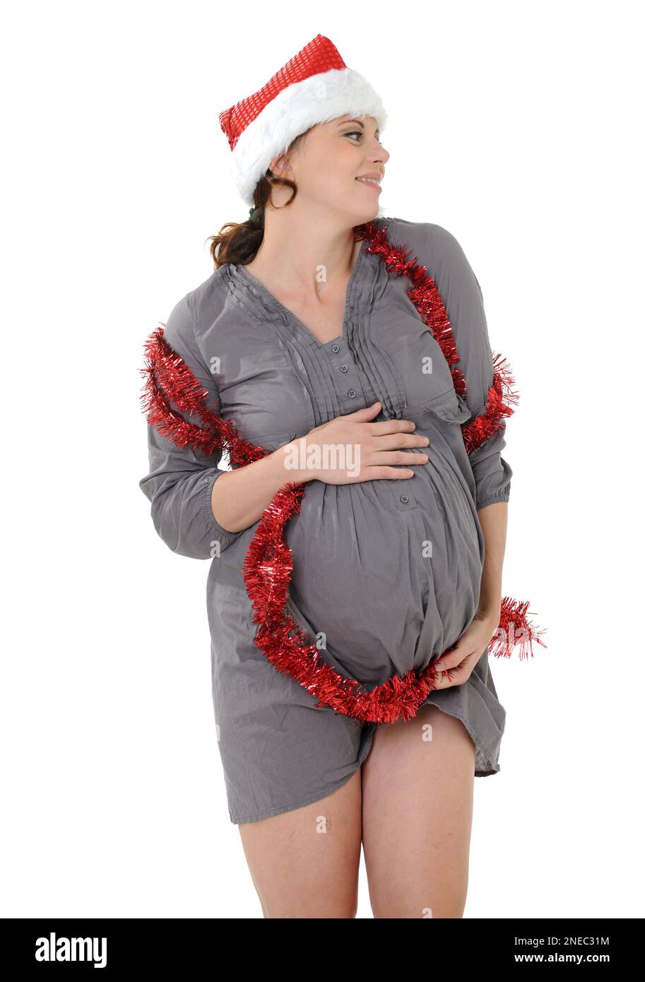 Pregnant young woman wearing santa hat and tinsel touching belly while  standing over white background Stock Photo - Alamy