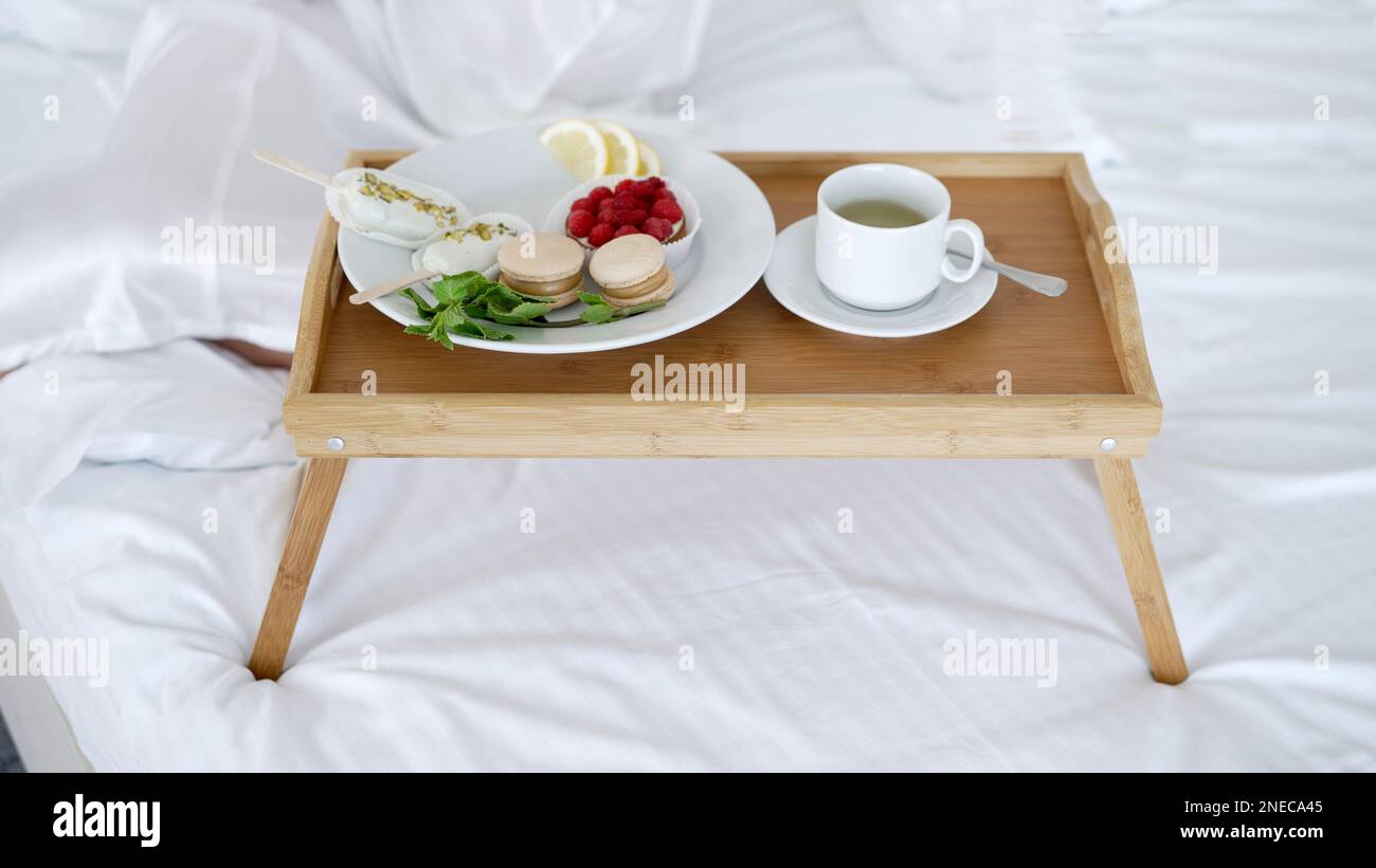 Tray with tasty breakfast on bed in light room. Wooden breakfast tray ...