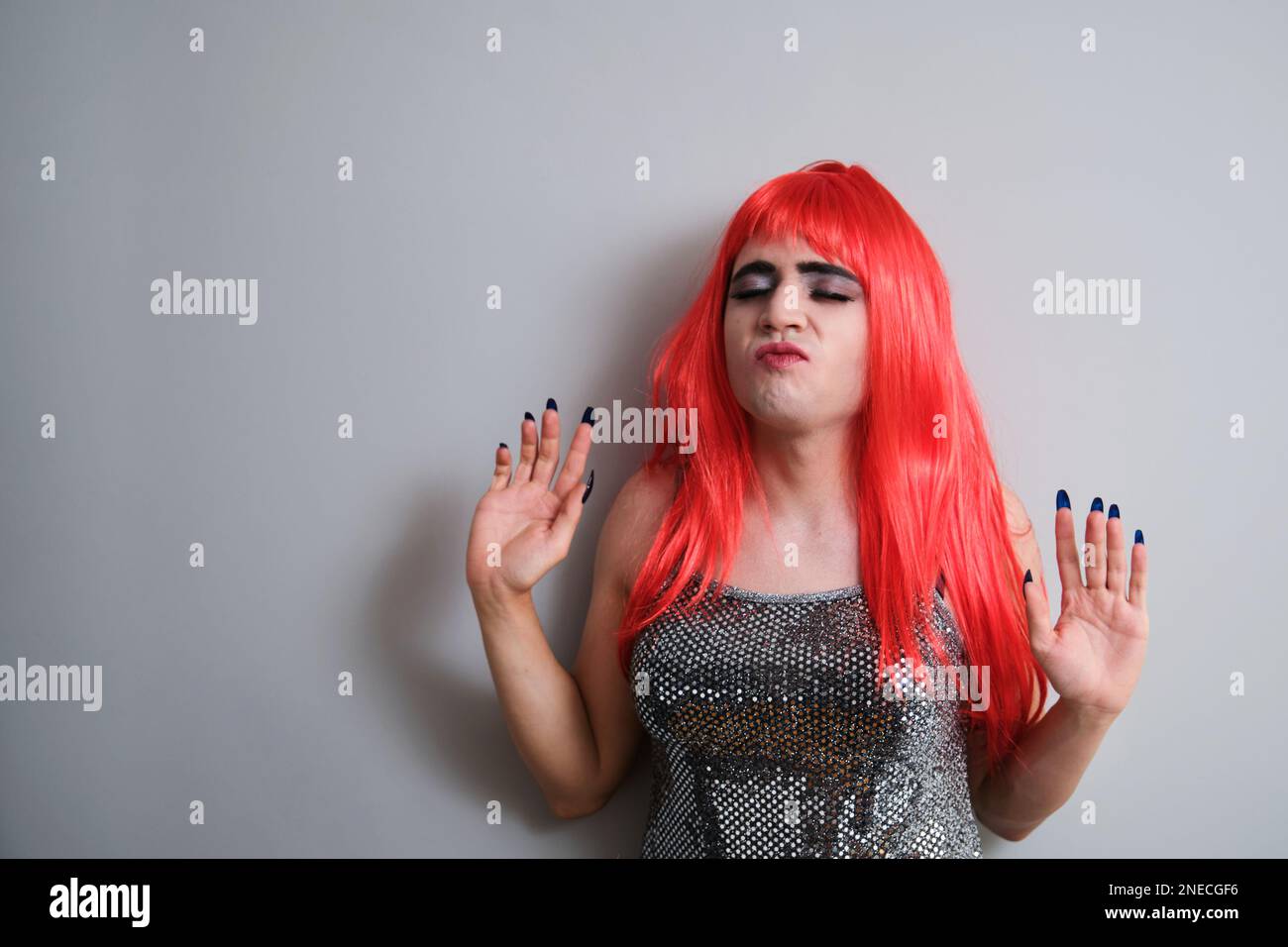 Portrait of transgender man dancing and wearing a red wig. Stock Photo