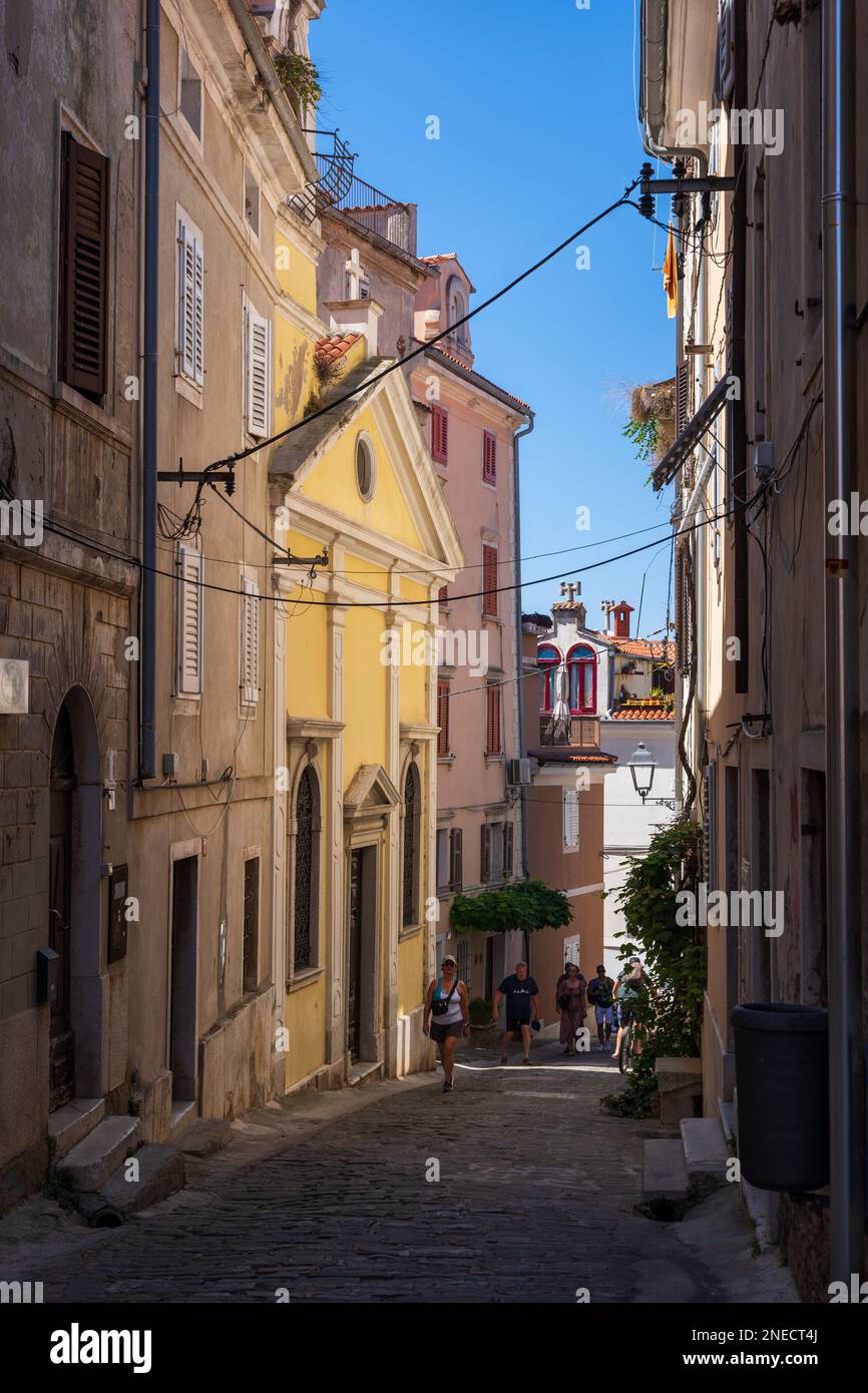 Town of Piran in Slovenia, Church of Our Lady of Consolation (Cerkev Marije Tolažnice) on narrow descending street in historic old town. Stock Photo