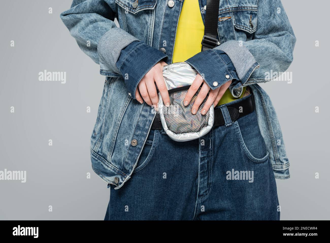 cropped view of model in stylish denim outfit and belt bag posing isolated on grey,stock image Stock Photo