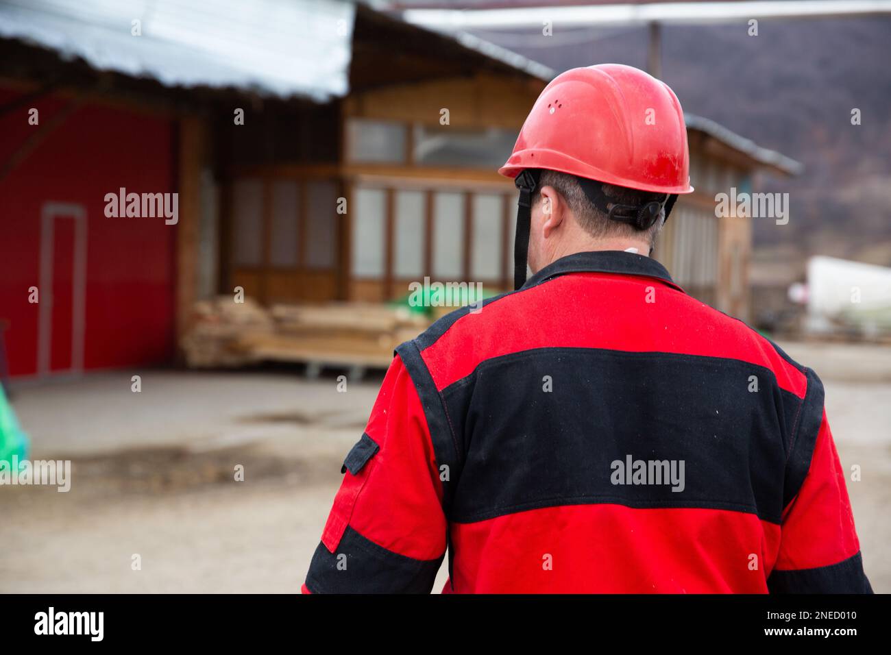 A closeup of a man in a red and black jacket wearing a safety helmet ...