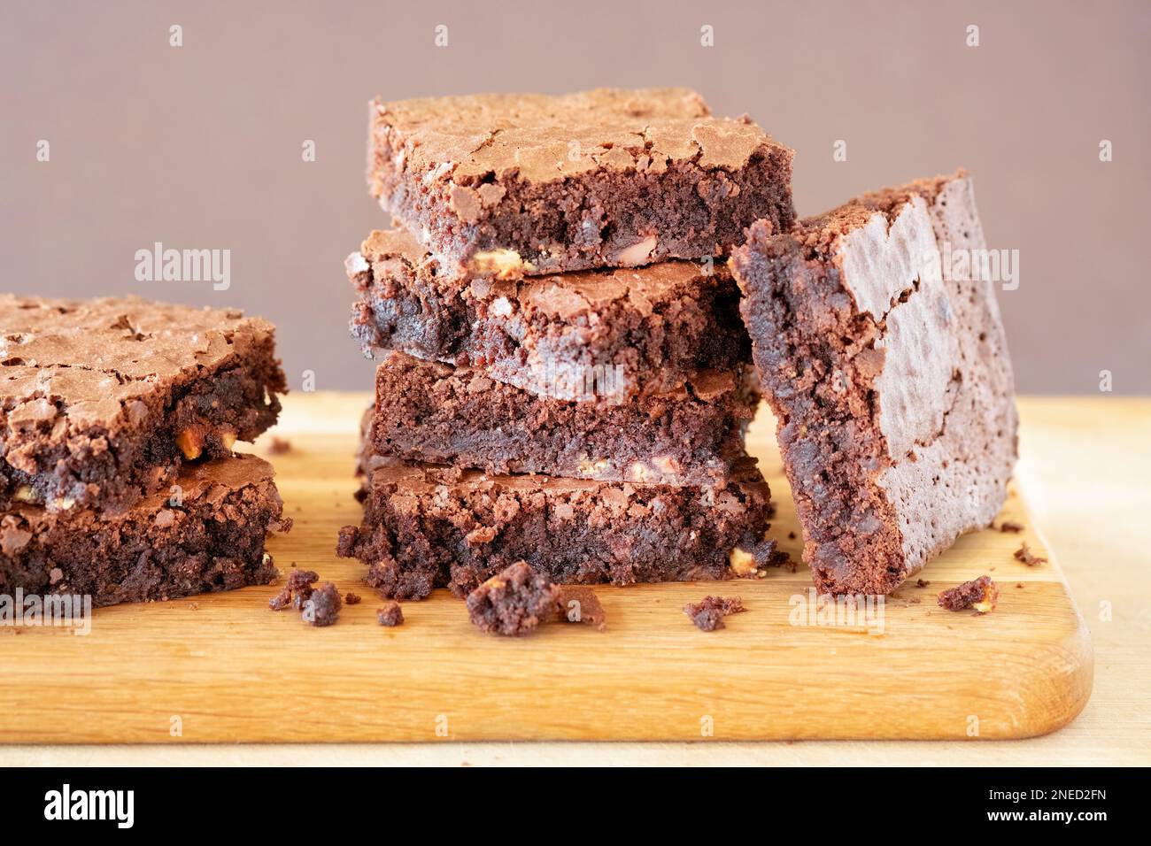 A batch of freshly home baked triple chocolate brownies arranged on a wooden serving board. The brownies are still warm and gooey. an indulgent treat Stock Photo