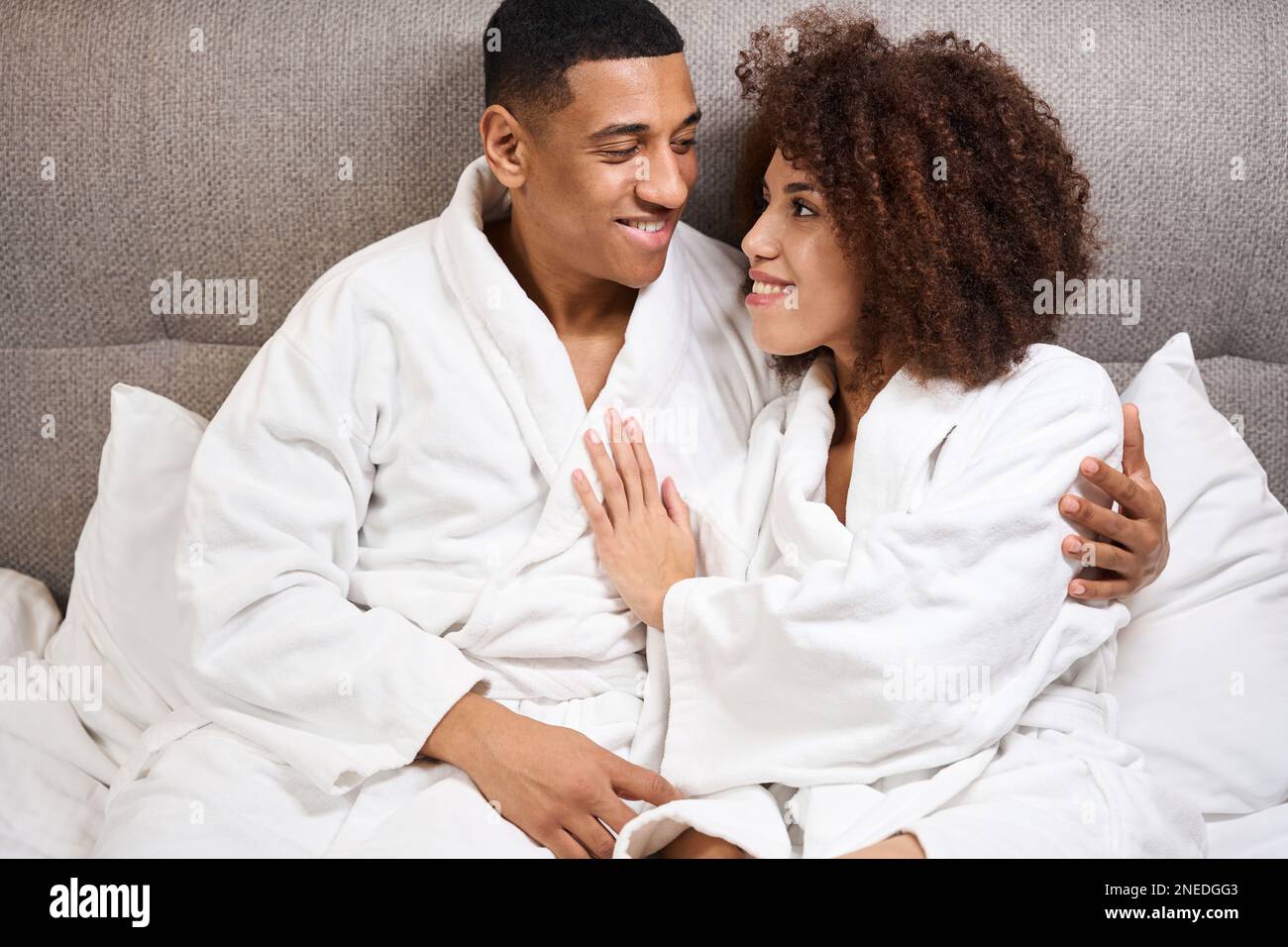 Curly woman and her boyfriend sit hugging on the bed Stock Photo - Alamy