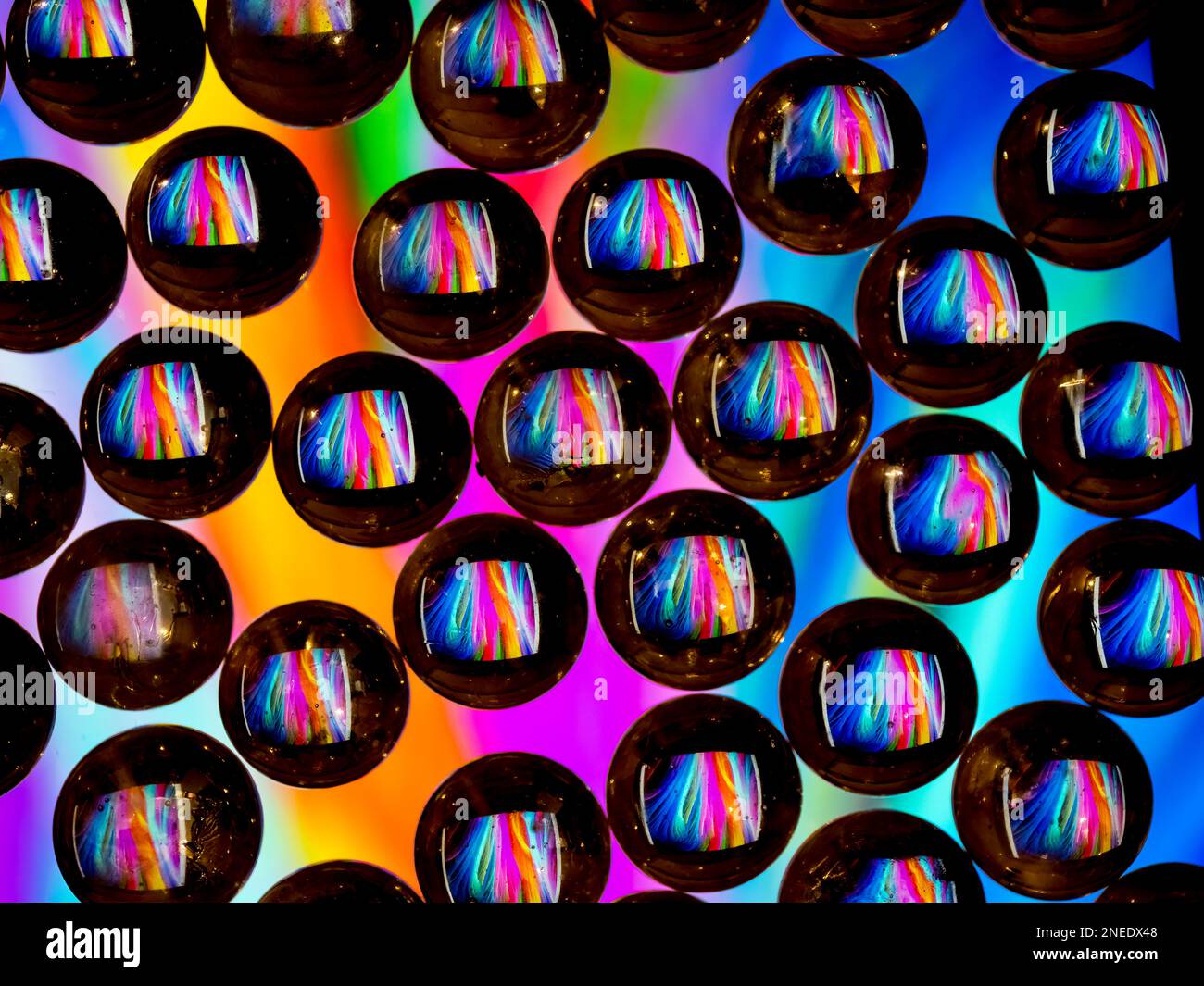 Colorful abstract pattern reflecting in black ringed glass drops Stock Photo
