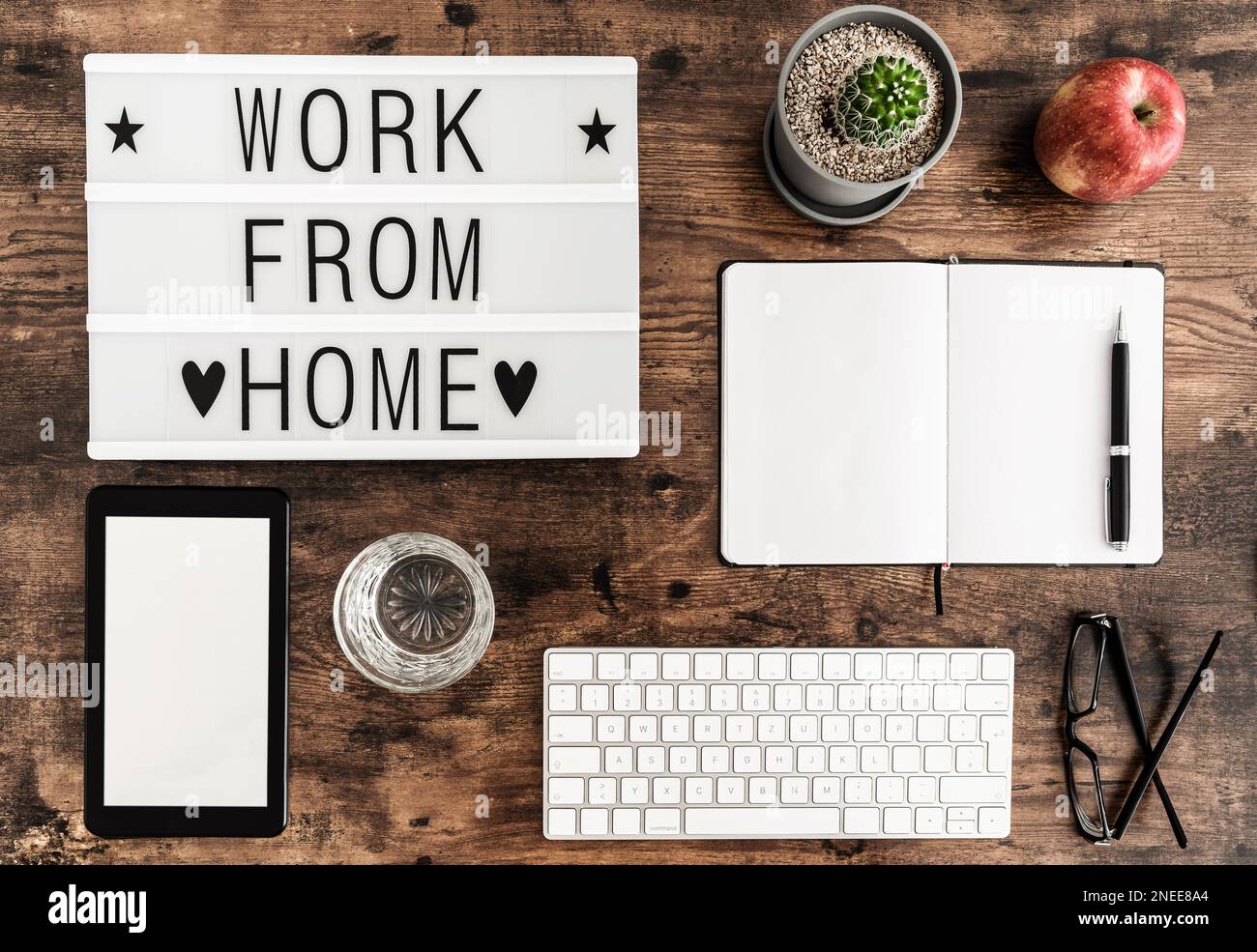 working from home during coronavirus covid-19 pandemic and home office concept, above shot of computer keyboard, lightbox and notepad on wooden table Stock Photo