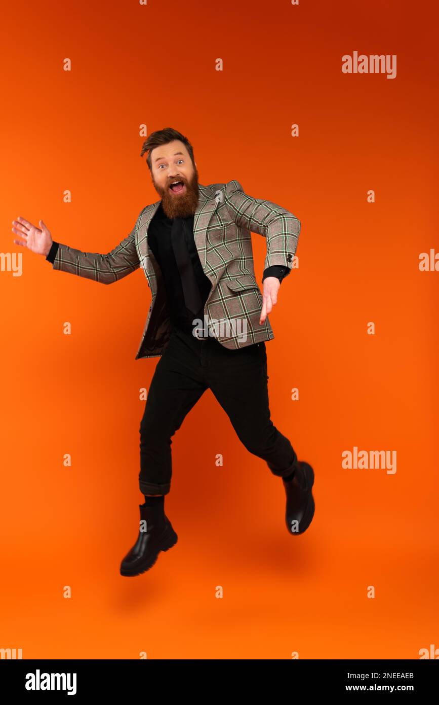 Excited stylish man jumping and looking at camera on red background,stock image Stock Photo