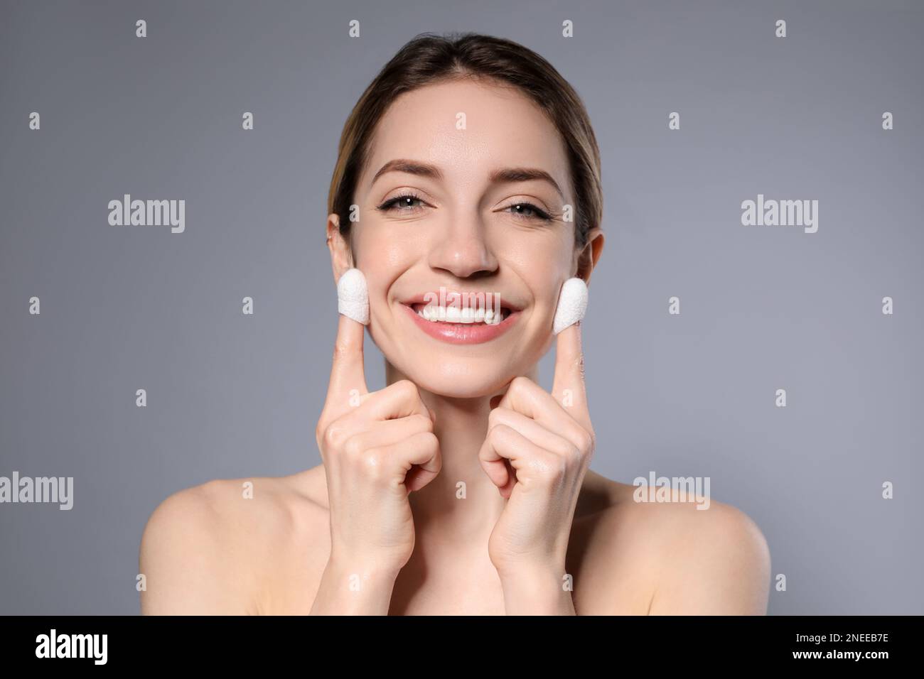 Woman using silkworm cocoons in skin care routine on grey background ...