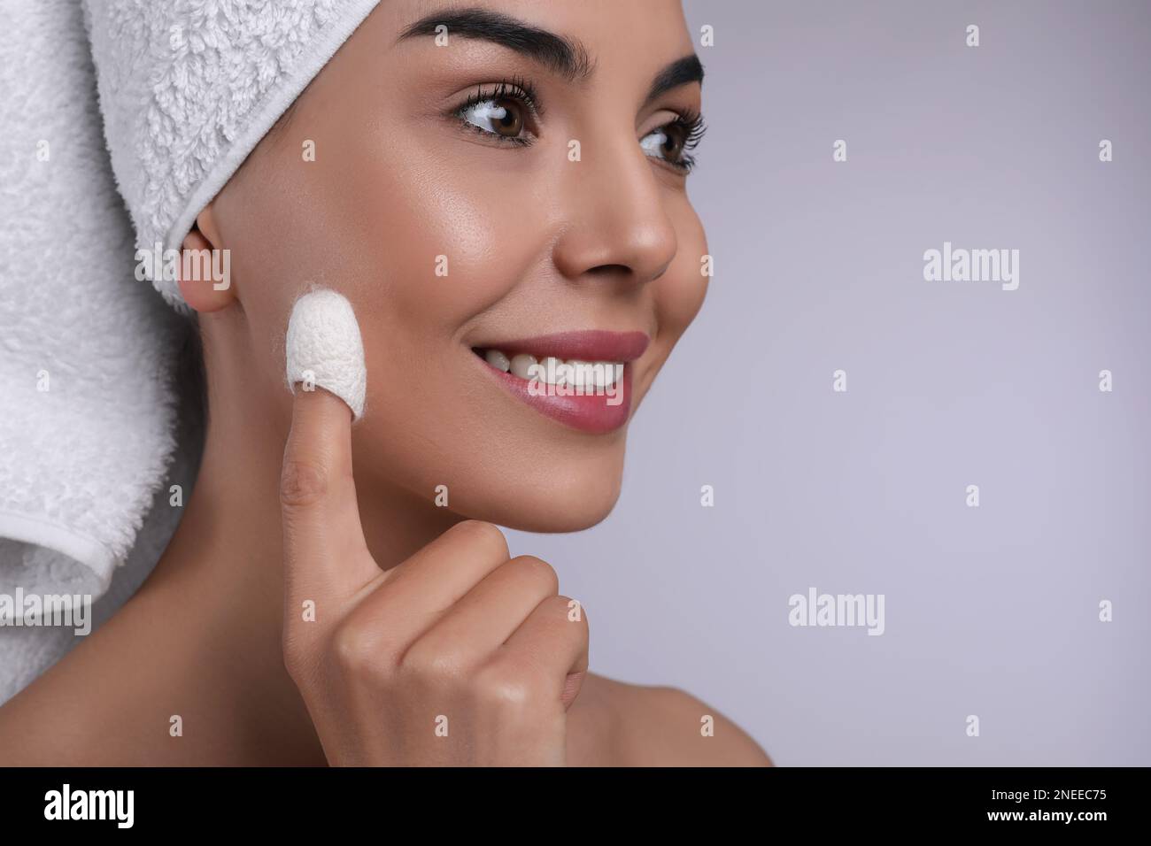 Woman using silkworm cocoon in skin care routine on light grey ...